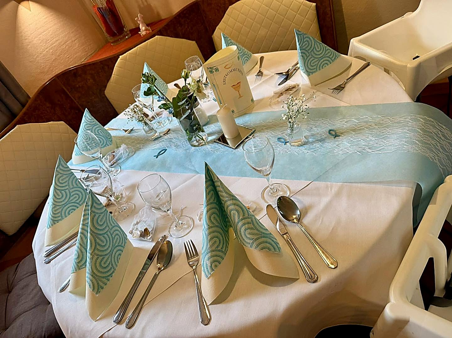 Liebevoll dekorierter runder Tisch mit Servietten und Blumen